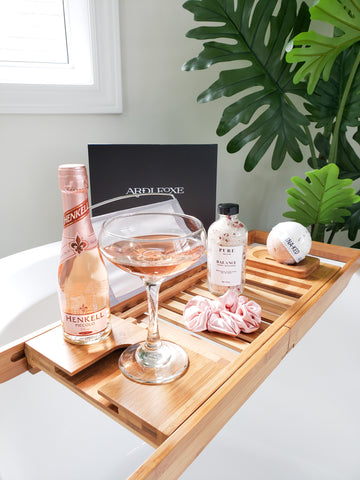 ardi foxe gift box with champagne in glass, bath salts, bath bomb, bath salts, and pink scrunchie in the bath tub for spa